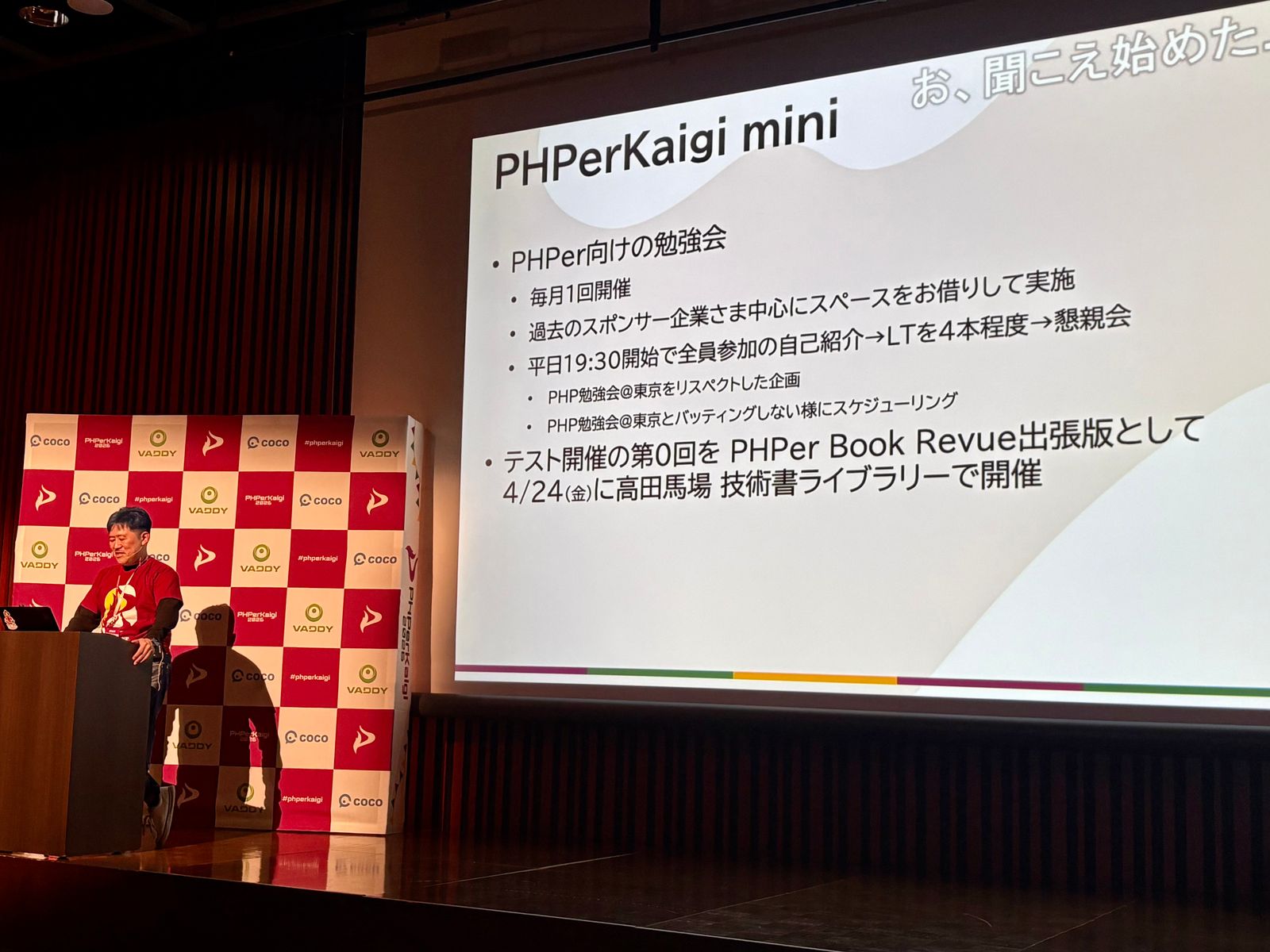 PHPerKaigi 2026のクロージングで長谷川さんからPHPerKaigi miniの開催がアナウンスされたときの写真。スライドに技術書ライブラリーで開催される旨が記載されている